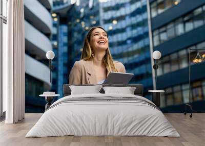 Portrait of a successful business woman using digital tablet in front of modern business building Wall mural