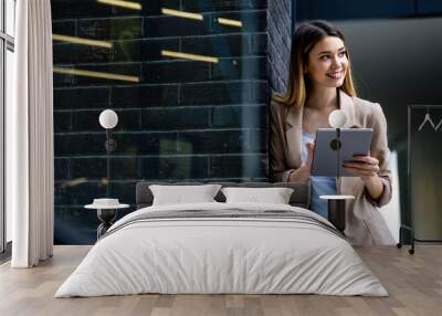 Portrait of a successful business woman using digital tablet in front of modern business building Wall mural