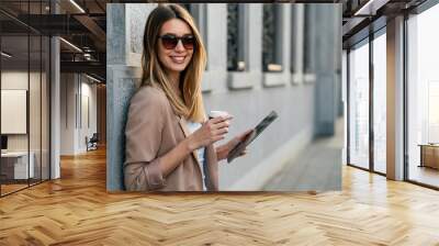 Portrait of a successful woman using digital tablet during quick break in urban background Wall mural