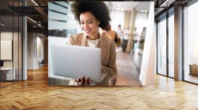 Portrait of an attractive young african businesswoman smiling while standing by windows in office Wall mural