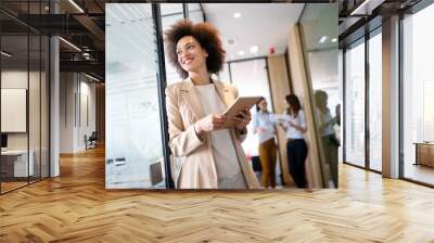 Portrait of an attractive young african businesswoman smiling while standing by windows in office Wall mural