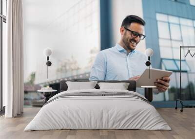 Portrait of businessman in glasses holding tablet Wall mural