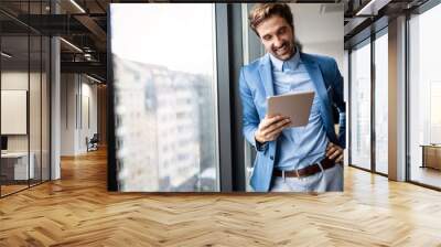 Portrait of businessman smiling while using digital tablet Wall mural