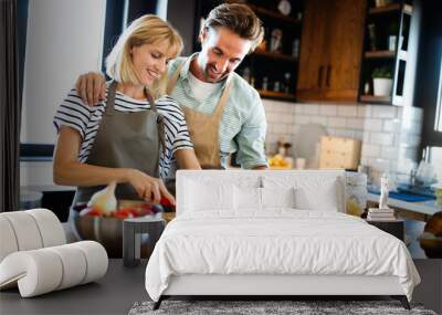 Portrait of happy young couple cooking together in the kitchen at home. Wall mural