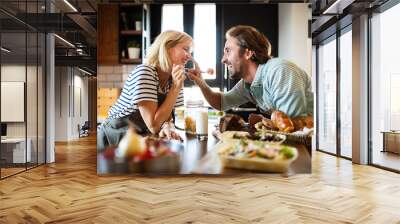 Portrait of happy young couple cooking together in the kitchen at home Wall mural