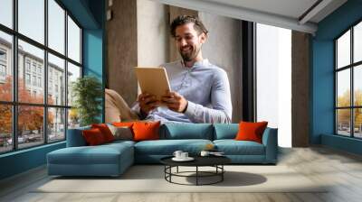 Portrait of successful handsome business man using digital tablet in office Wall mural