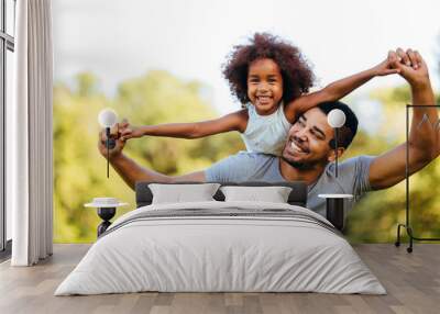 Portrait of young father carrying his daughter on his back Wall mural