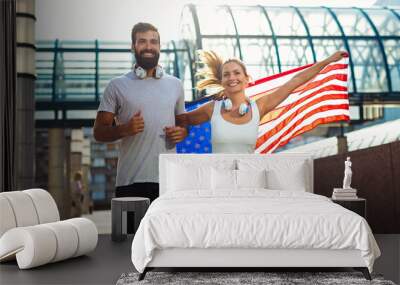 Portrait of young happy fitness couple exercising and having fun together outside with USA flag. Wall mural