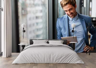 Portrait of young success business man with digital tablet in corporate office Wall mural