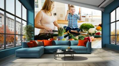 Pregnant woman preparing meal with son Wall mural