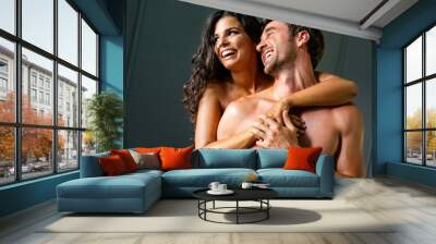 Sensual young couple together in bed. Happy couple in bedroom enjoying sensual foreplay. Wall mural