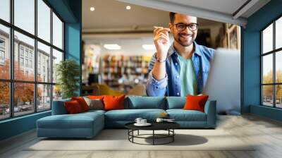 Smiling male student working and studying in a library Wall mural