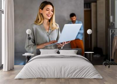 Smiling pretty woman using laptop for work freelance social media or relaxation. Wall mural