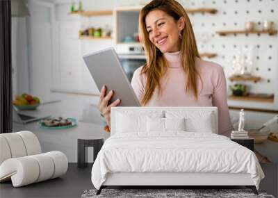 Smiling young woman with tablet in the kitchen Wall mural