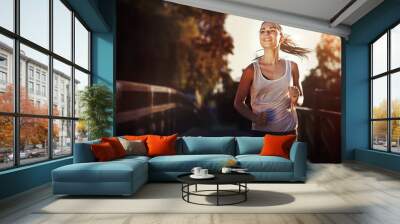 Sporty female jogger running and training outside Wall mural