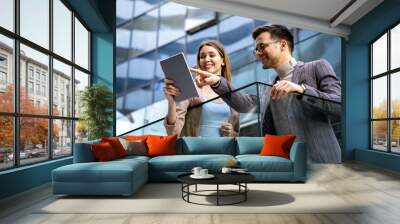 Successful young business people talking, working together in front of modern business building Wall mural