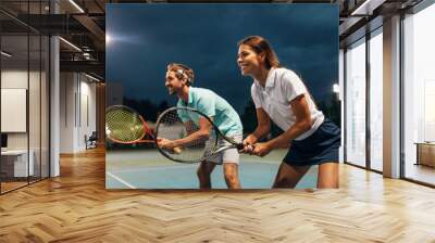 Tennis sport people concept. Mixed doubles player hitting tennis ball with partner standing near net Wall mural