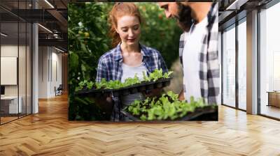 Two attractive young women working in greenhouse and planting seeds. Wall mural