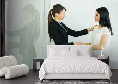 two businesswomen shakig hands in an office Wall mural