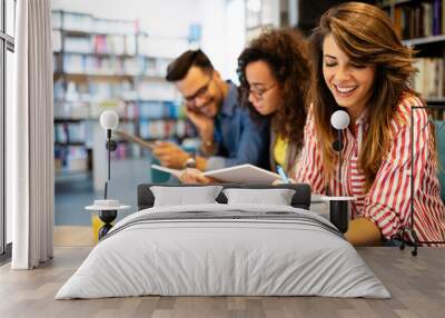 University students in cooperation at library. Group of young friends reading books. Wall mural