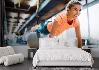 Young attractive woman doing push ups using ball Wall mural