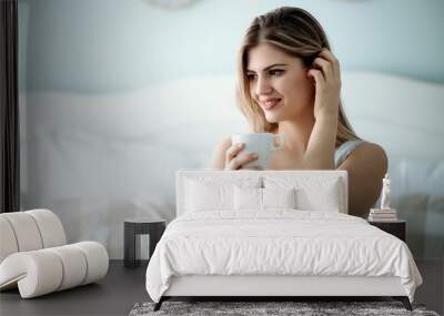 Young beautiful woman sitting on bed at home Wall mural