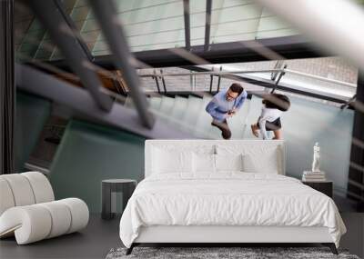 Young business people climb the stairs in the office Wall mural