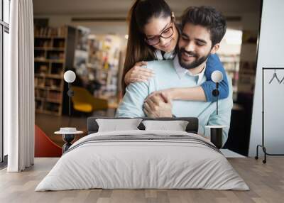 Young couple reading books and studying together in library Wall mural