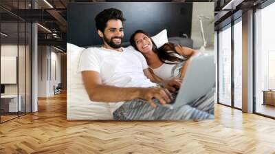 Young couple with laptop in the bed in room Wall mural