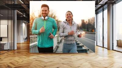 Young fitness couple running in urban area Wall mural