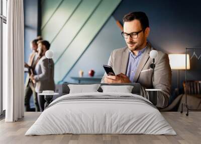 Young handsome businessman using smartphone in the office Wall mural