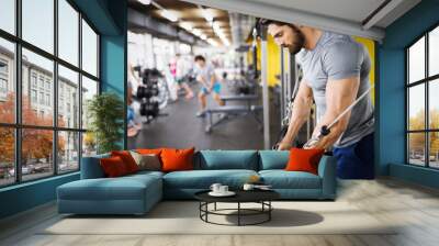 Young handsome man doing exercises in gym Wall mural