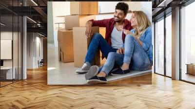 Young happy couple moving in new home and unpacking boxes Wall mural