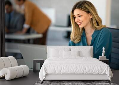 Young happy successful business woman working with laptop in corporate office Wall mural