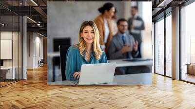 Young happy successful business woman working with laptop in corporate office Wall mural