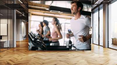 Young people running on a treadmill in health club. Wall mural