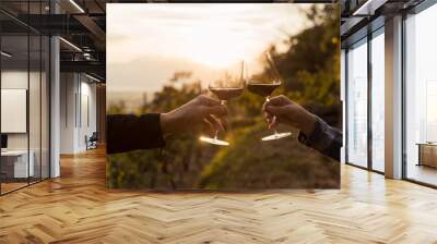 Two hands clinking red wine glass in a Vineyard during sunset Wall mural