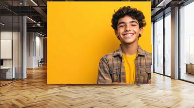 A joyful Latino Hispanic teen boy with a big smile on a vibrant yellow background. Wall mural