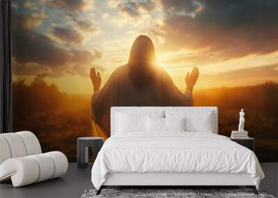 Rear view of Jesus Christ with raised hands praying to God against a sunrise sky background. Wall mural