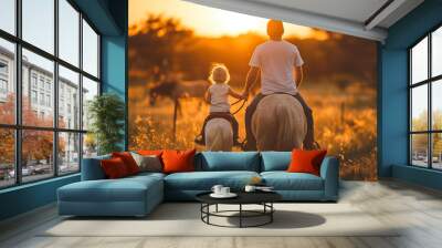 Portrait of father and young daughter holding hands and riding horses together outdoors at sunset Wall mural