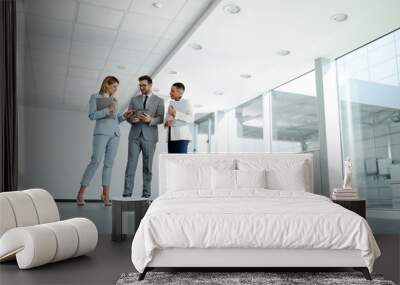 Business people in elegant clothes working together and smiling while standing in the office hallway Wall mural