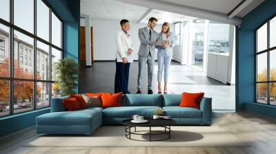 Business people in elegant clothes working together and smiling while standing in the office hallway Wall mural