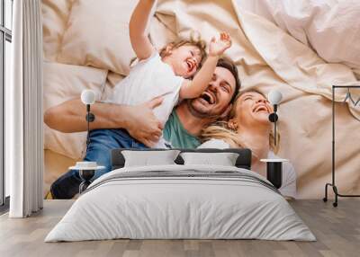 Happy family having fun in the bedroom while they lie on bed Wall mural