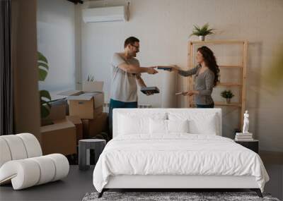 Photo of young couple packing boxes on moving day. Young couple is packing books because they are moving out from current flat. Wall mural