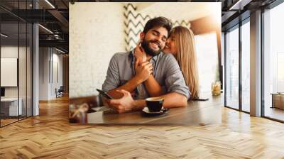 Portrait of a beautiful couple while having romantic moments in cafe. Girl hugging her handsome boyfriend. Wall mural