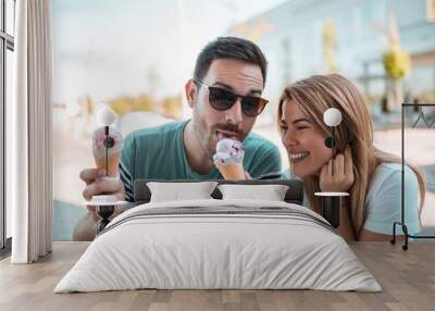 Young couple sharing ice cream while enjoying sunny weather outdoors Wall mural