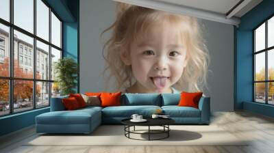 Zoe - Playful Blonde Toddler Girl Sticking Out Tongue, Lighthearted Fun Wall mural