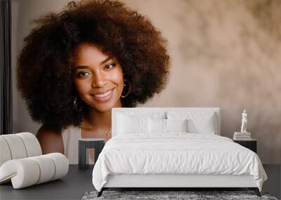 Beauty portrait of African American woman with clean healthy skin on beige background. Smiling dreamy beautiful black woman. Curly hair in afro style Wall mural