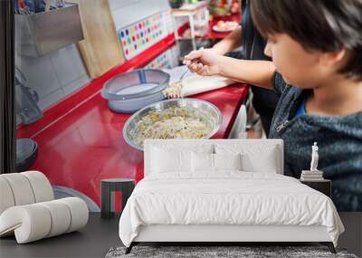 Happy mom and her little son cooking together in the kitchen, smiling mother teaching little boy to prepare food, cooking at home on the weekend Wall mural