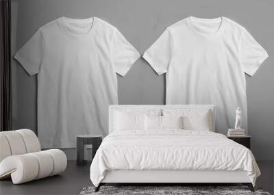 Two white t-shirts are neatly displayed on a plain gray background. The t-shirts are the focal point of the image, showcasing their simple design against the muted backdrop Wall mural